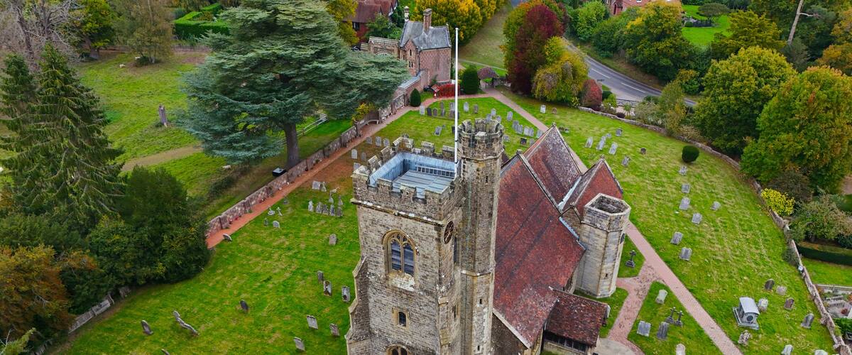 A historic church with a bell tower, surrounded by a cemetery.