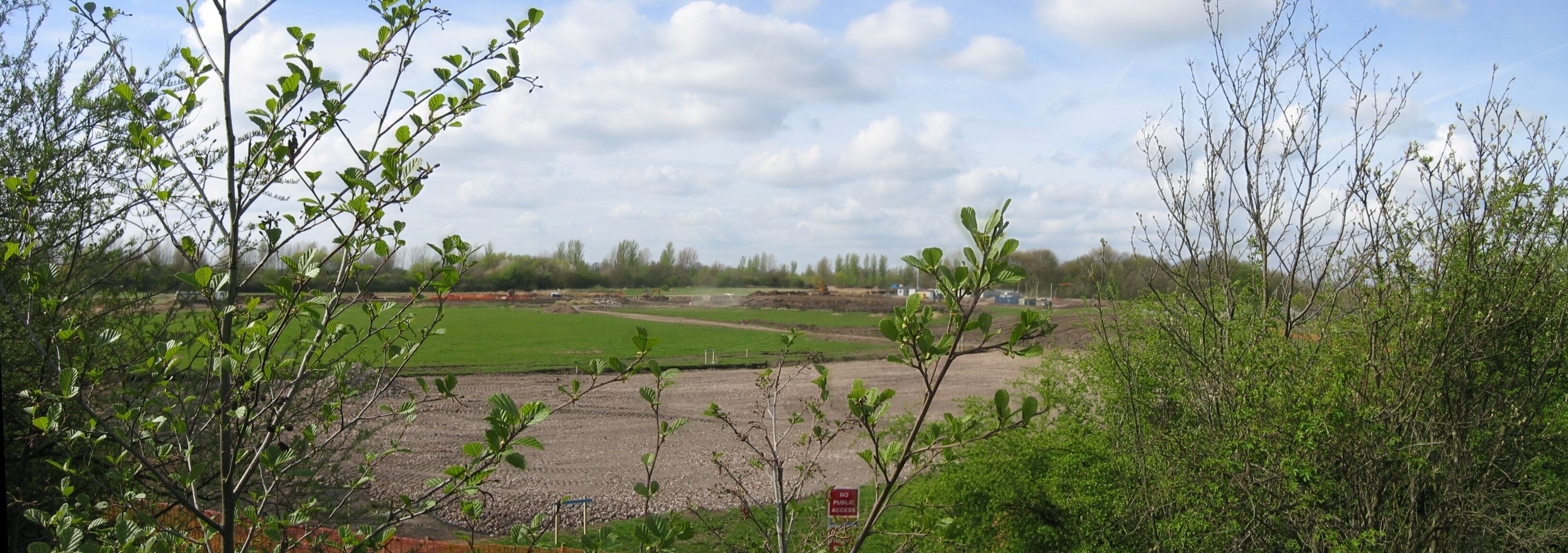 Panoramic photograph of Leigh Sports' Village (before it existed). This photo shows the fields being ploughed up by the heavy machinery. The area has been sectioned off and the work is well under-way.
