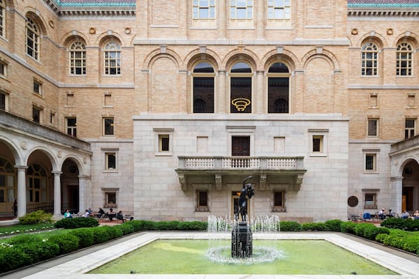 A historic building with a central courtyard, a fountain, and people sitting at tables.
