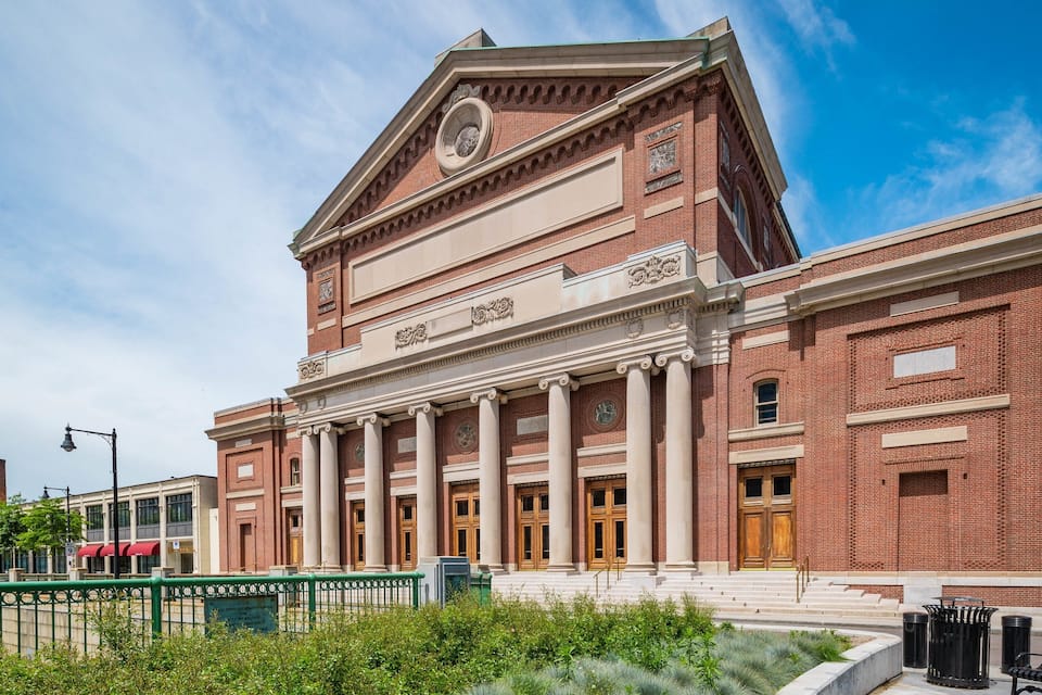 A large brick building with columns and a clock.