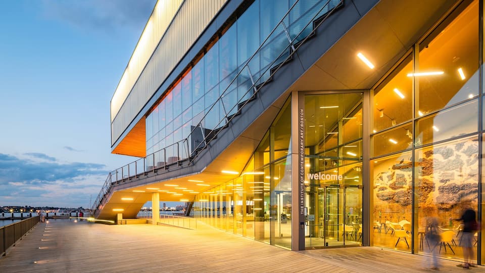 Un bâtiment moderne doté d’une façade en verre et d’une terrasse en bois.