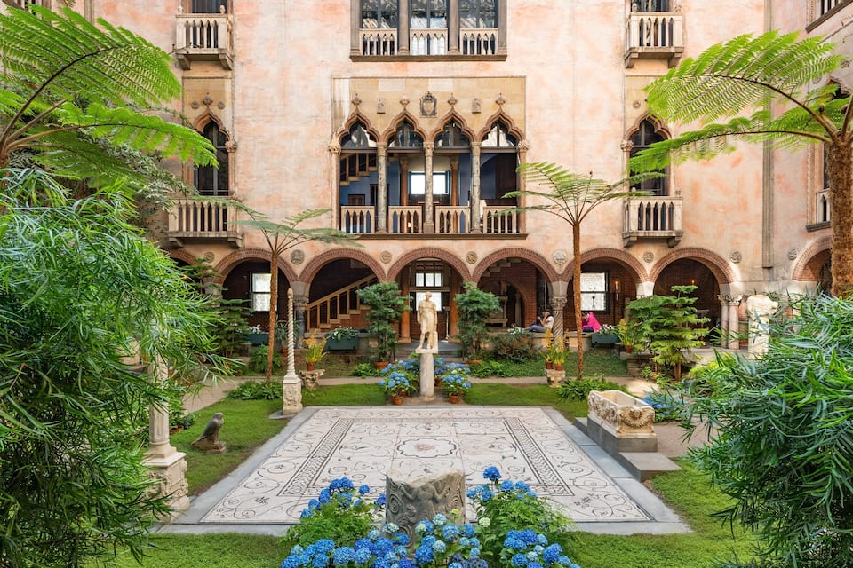 A courtyard with a central fountain, surrounded by arches and lush greenery.
