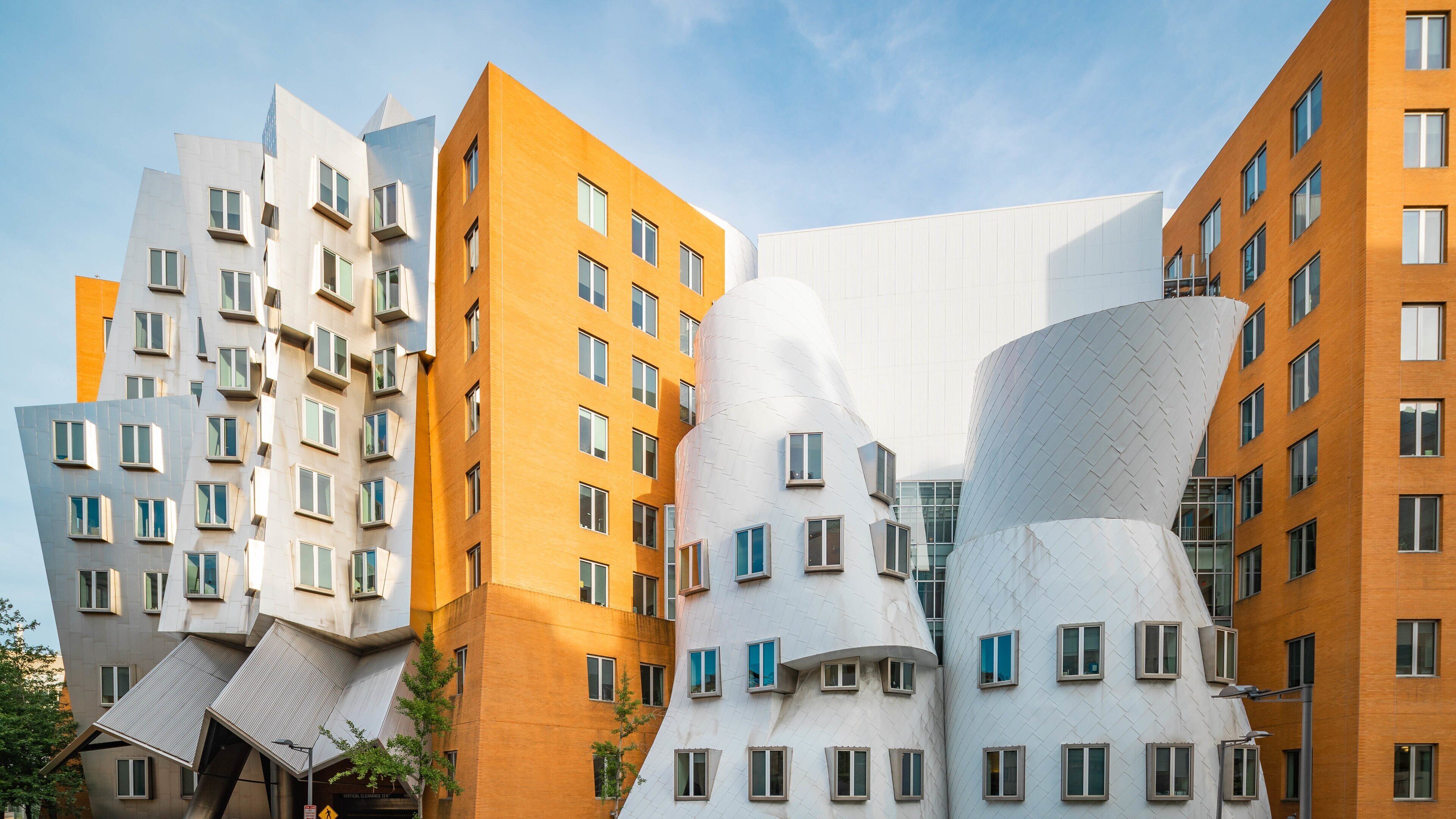 A modern architectural complex with unique curved and angular designs, featuring multiple buildings with varying facades in white, orange, and grey.