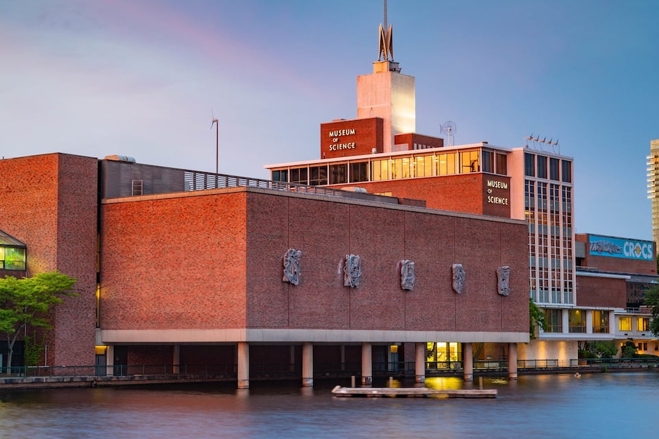 Edificio de un museo de ciencia con una torre destacada y un río en primer plano.