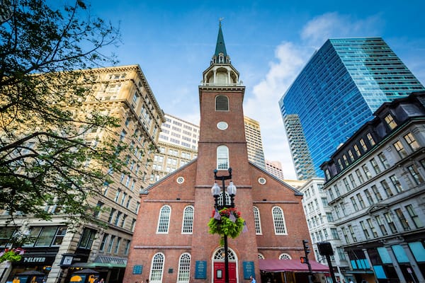 Une église historique, reconnaissable à son clocher imposant, entourée de gratte-ciel modernes et d’immeubles plus anciens.