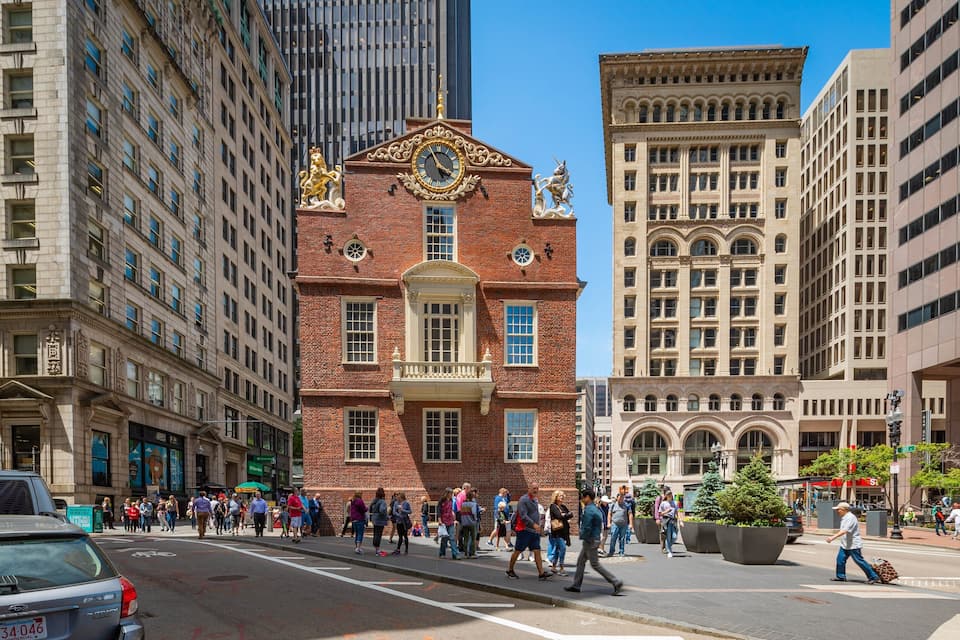 A busy urban street with historic buildings, pedestrians, and modern high-rises.