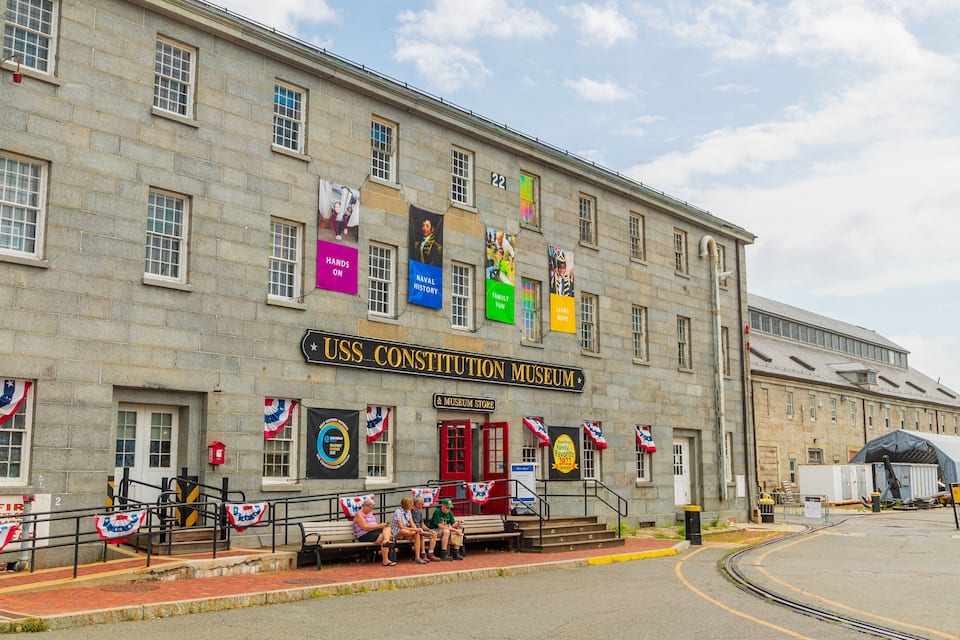 The USS Constitution Museum building with multiple colorful banners and flags.