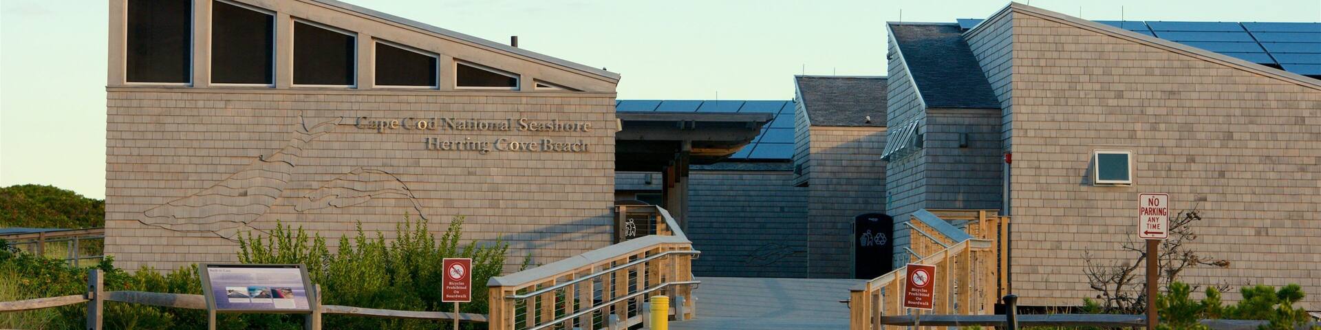 A building with a sign reading "Cape Cod National Seashore Herring Cove Beach" and a no parking sign.