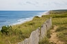 A coastal path with a wooden fence leading to a beach.