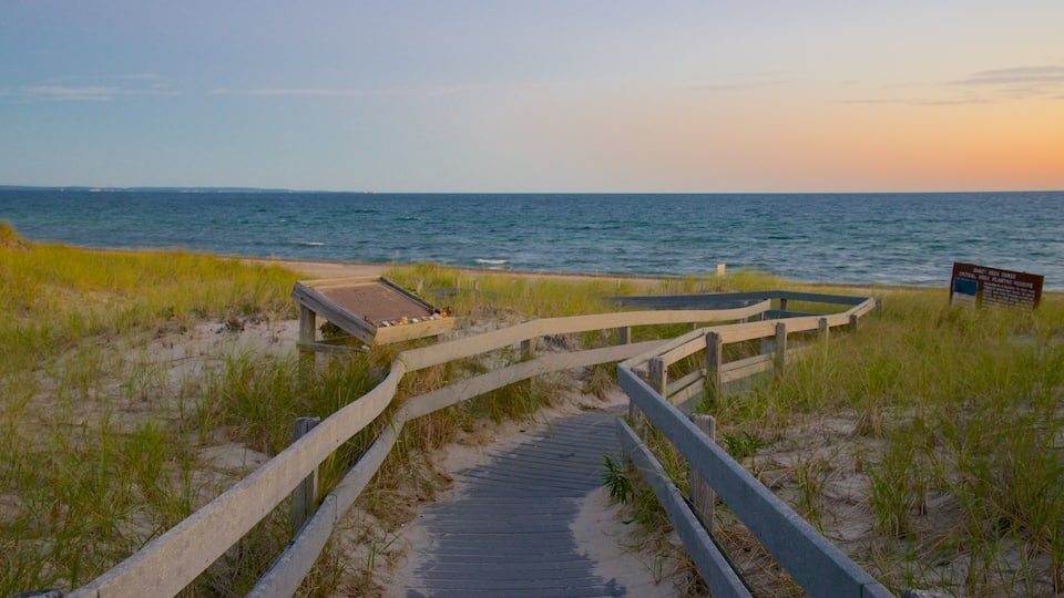 A wooden boardwalk leading to the beach, surrounded by sand and grass.