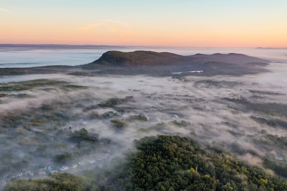 A misty landscape with rolling hills and scattered buildings.