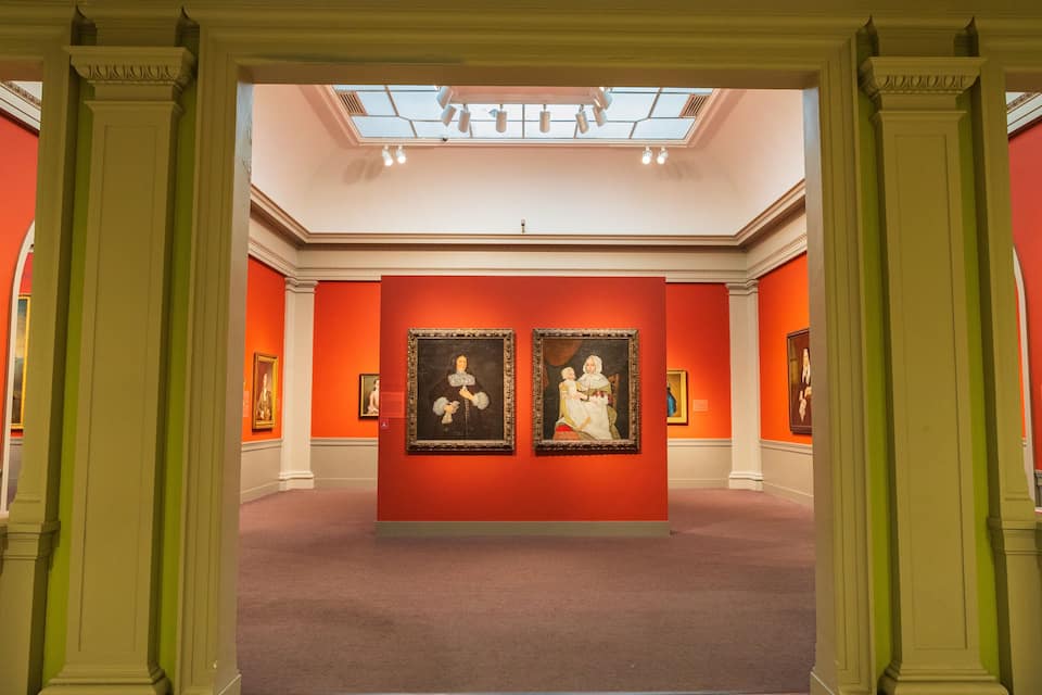 Uma galeria de arte com paredes vermelhas e arquitetura clássica.