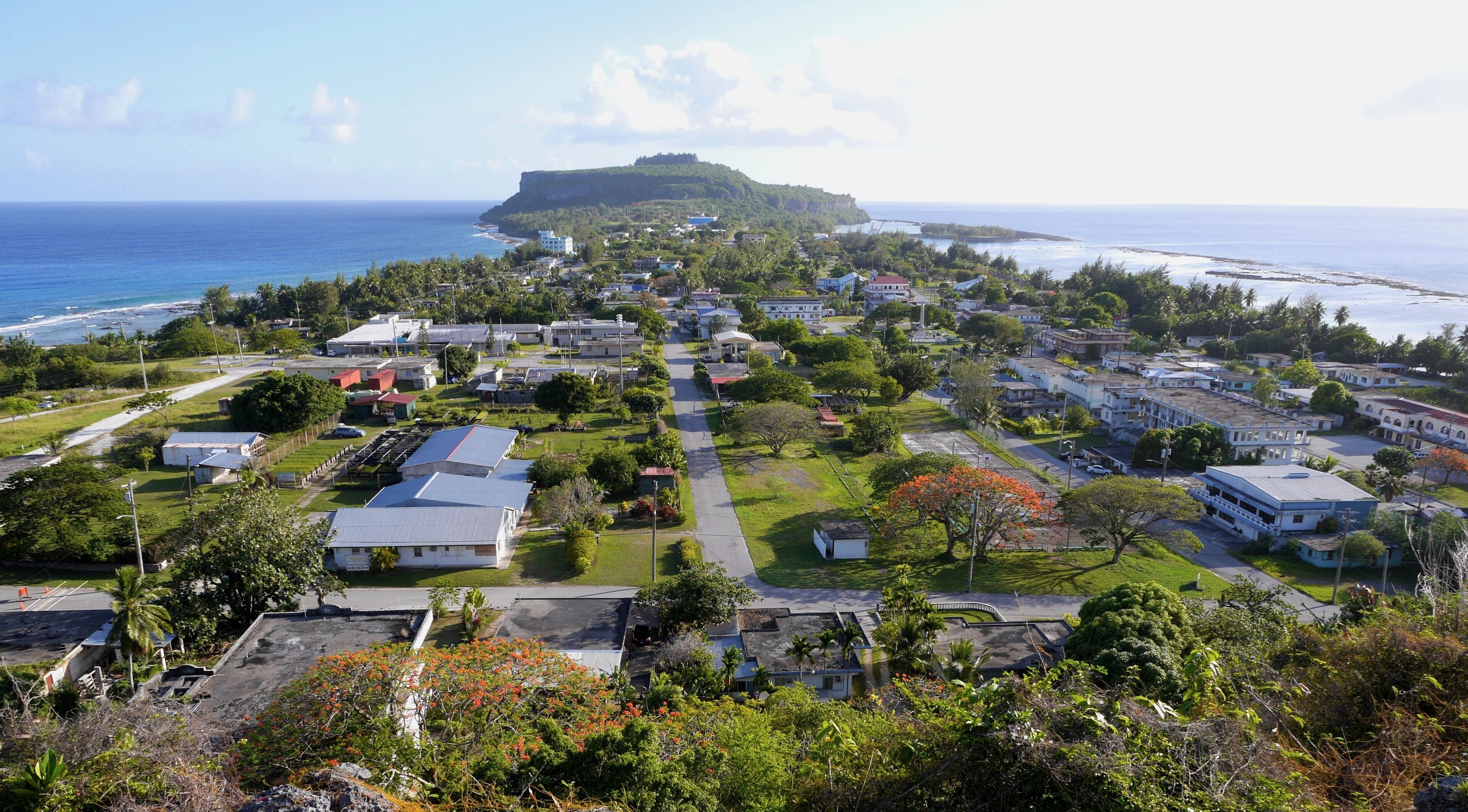 A coastal town with buildings, roads, and a prominent hill in the background.