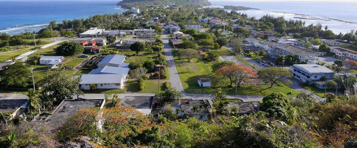 A coastal town with buildings, roads, and a prominent hill in the background.