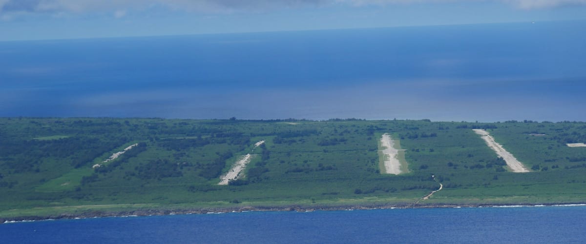 A coastal landscape with a series of parallel paths or roads leading towards the sea, surrounded by green vegetation.