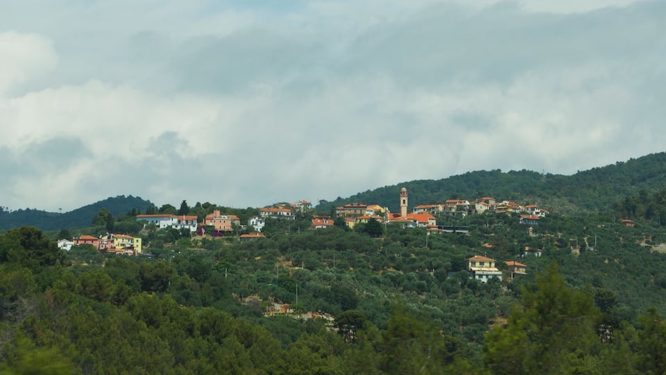 A hillside village with red-roofed houses and a prominent church tower.