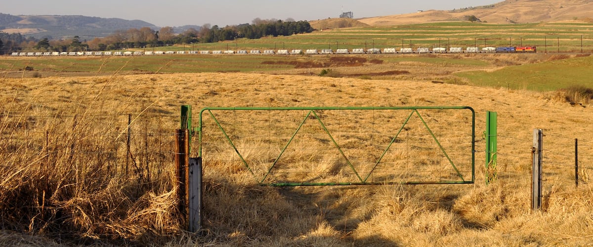 A train in a rural landscape with fields and hills.