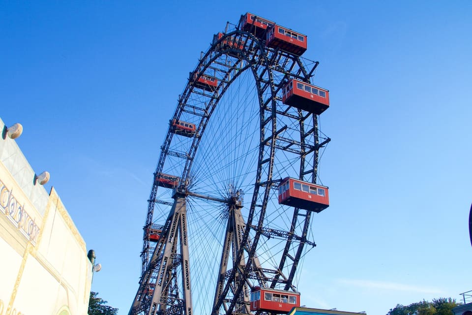 A large Ferris wheel with cabins numbered 14, 16, 18, and 20 against a clear blue sky.