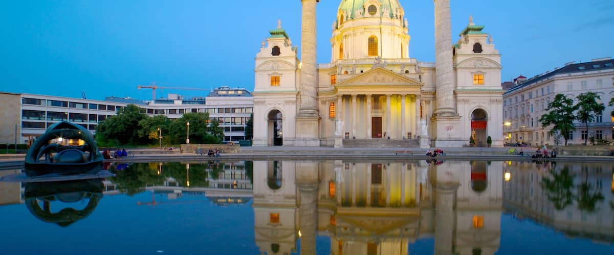 A grand cathedral with a large dome and twin towers, reflecting in a calm water body in front.