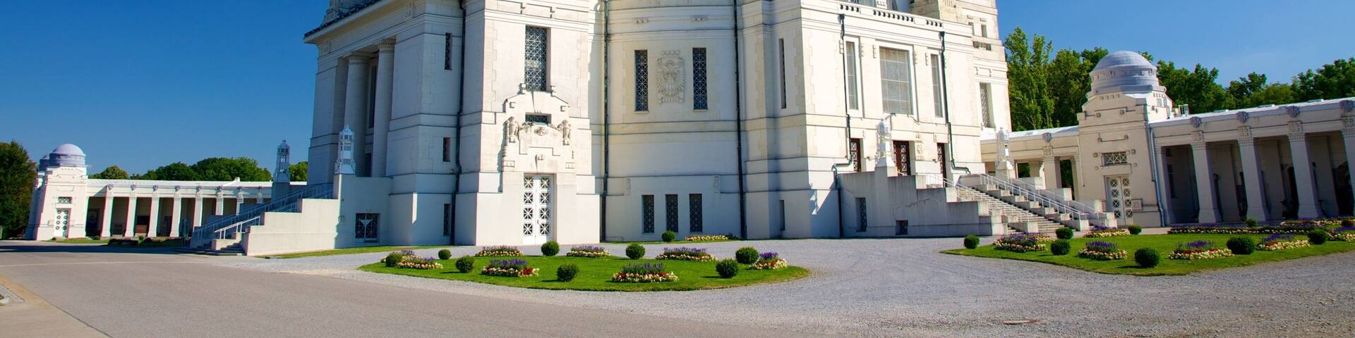 A large white building with a green dome and multiple smaller domes, surrounded by a well-maintained garden.