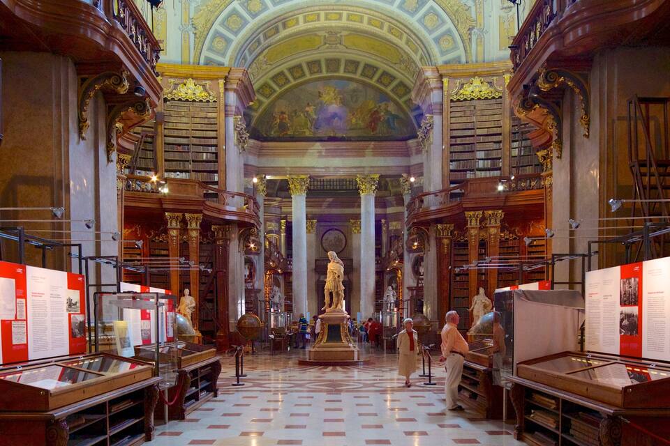 Interior d'una biblioteca ornamentada amb alts sostres, fusteria detallada i una estàtua central.