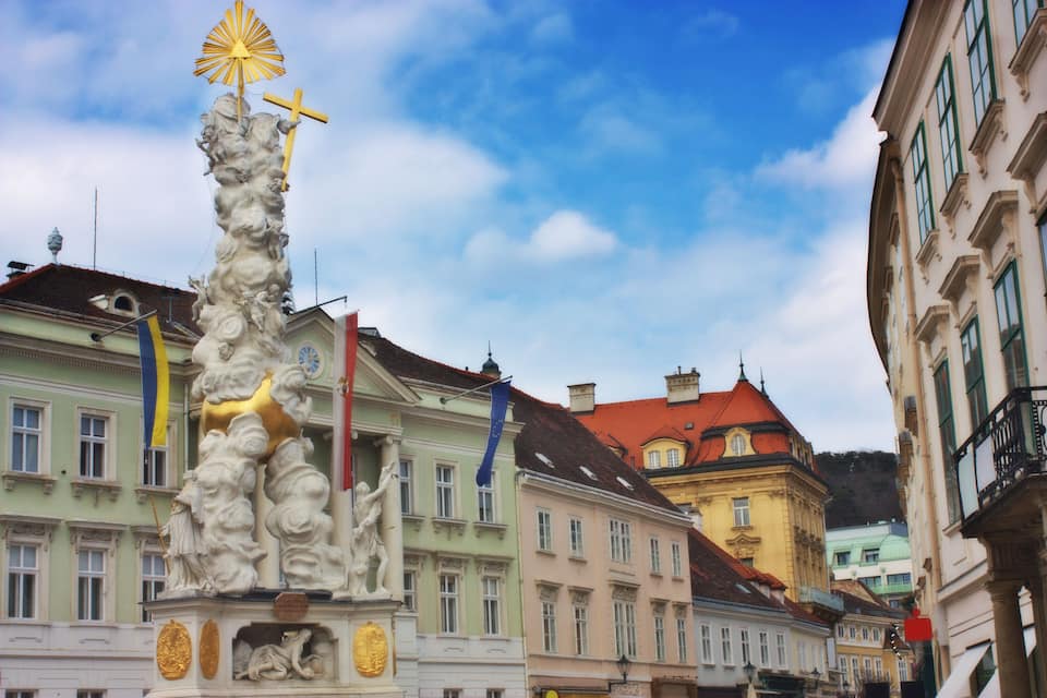 Un edificio histórico con arquitectura clásica, una estatua y banderas.