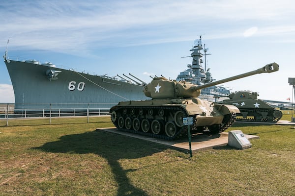 Ein Militärtank und ein großes Kriegsschiff mit der Nummer 60 an der Seite.