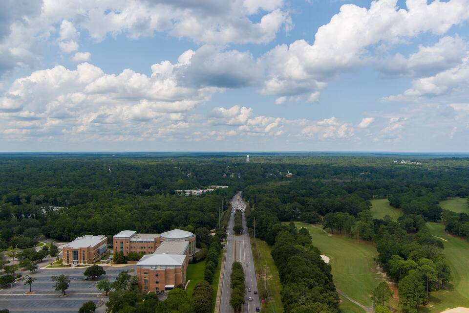 Vista aérea de un campus con edificios, una carretera y follaje circundante.