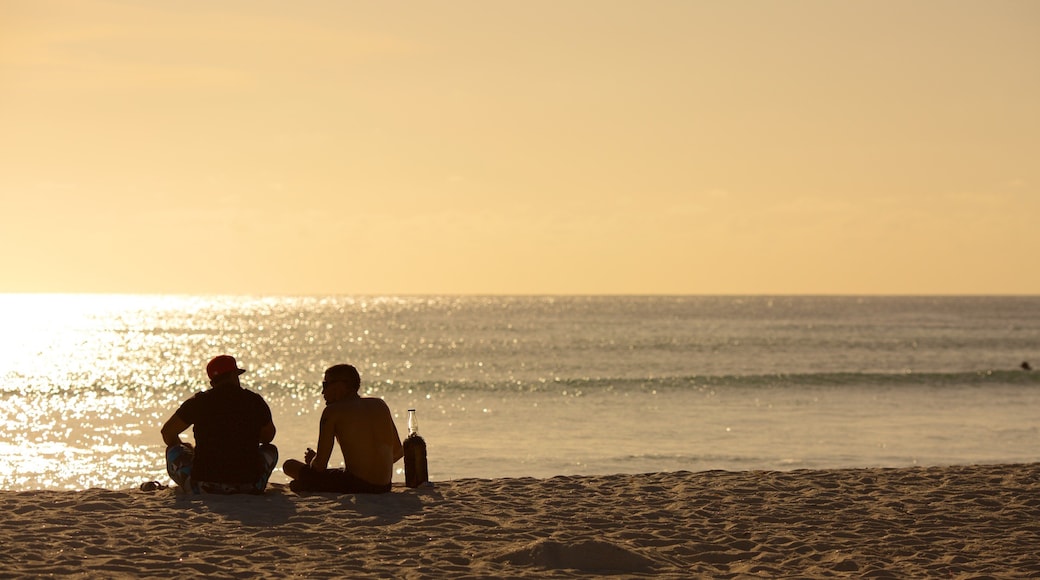 Arashi Beach which includes a sandy beach and a sunset as well as a small group of people