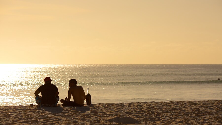 Arashi Beach which includes a sandy beach and a sunset as well as a small group of people