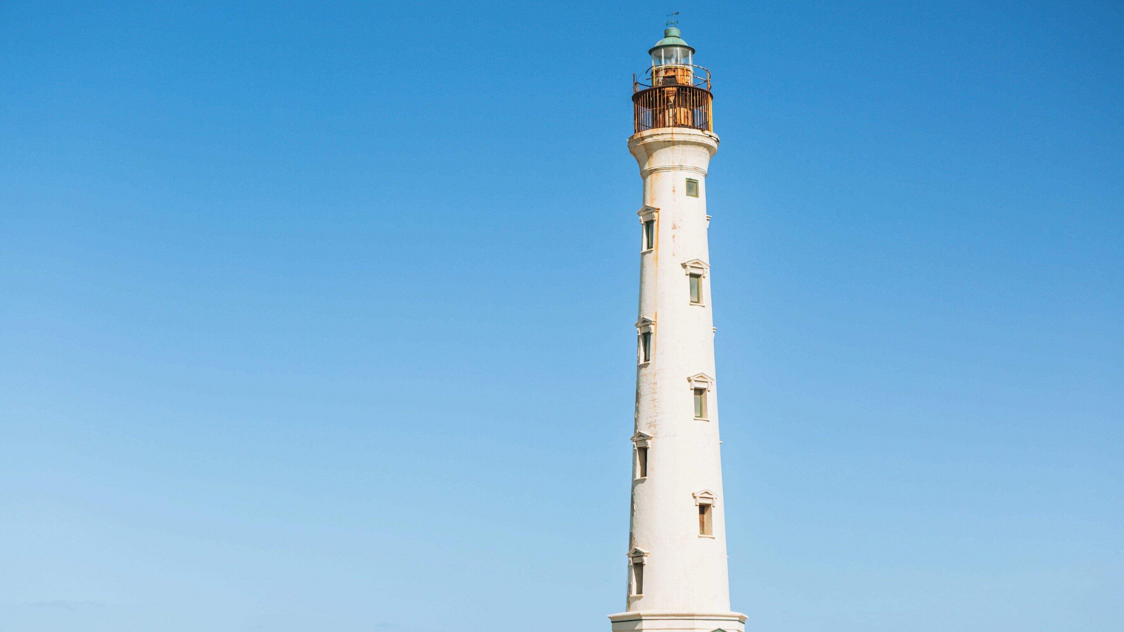 California Lighthouse stands tall against the clear blue sky in Noord, Aruba, showcasing the island's natural beauty and coastal charm