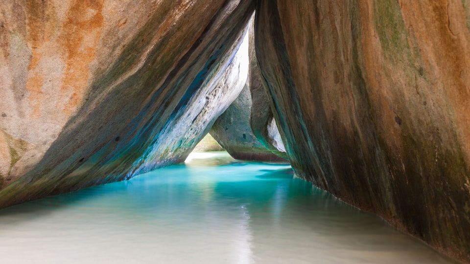 A cave with turquoise water and rock formations.