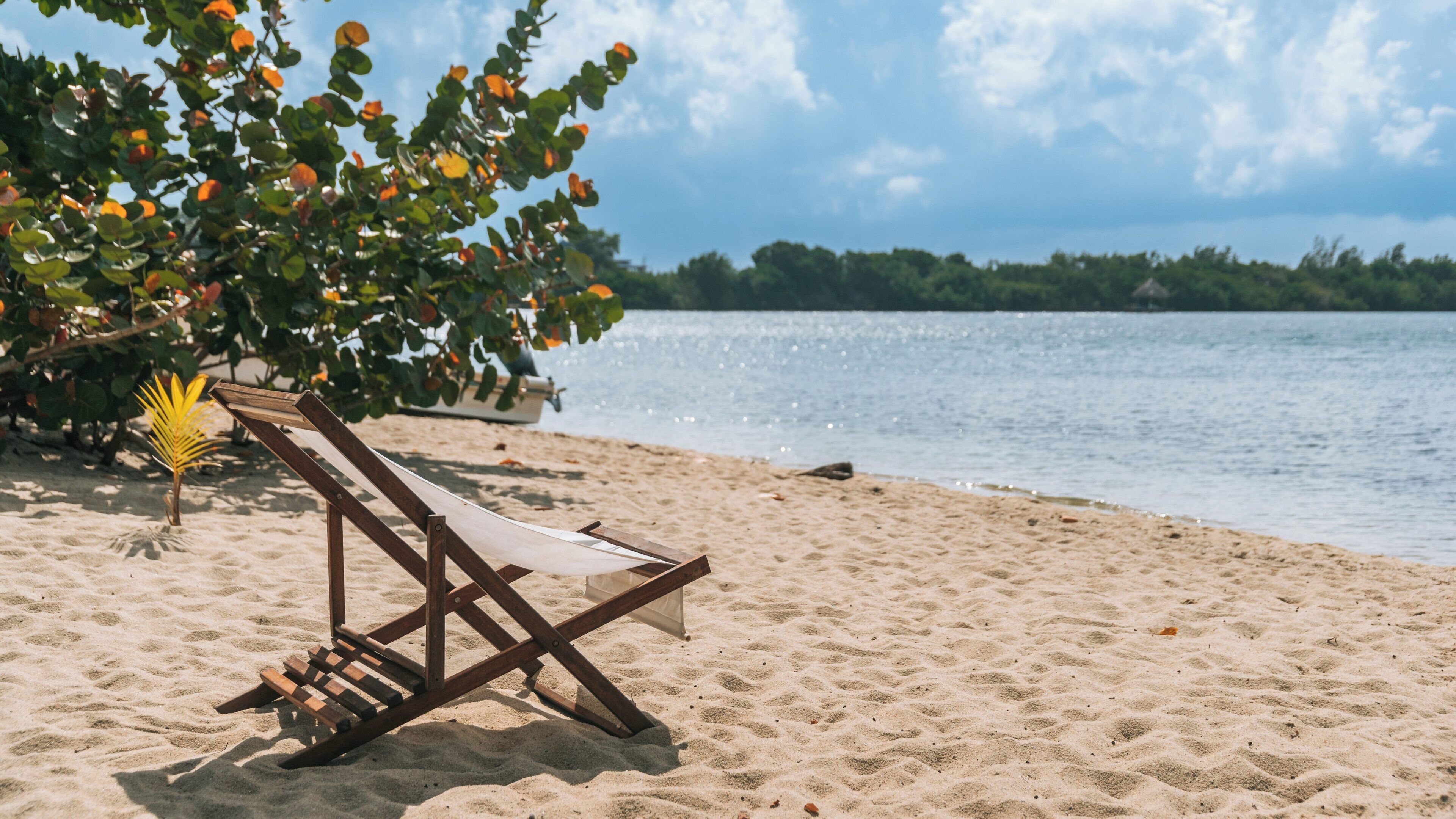 Relaxation by the serene waters of Placencia Beach in Stann Creek District, Belize, showcases golden sands and lush greenery
