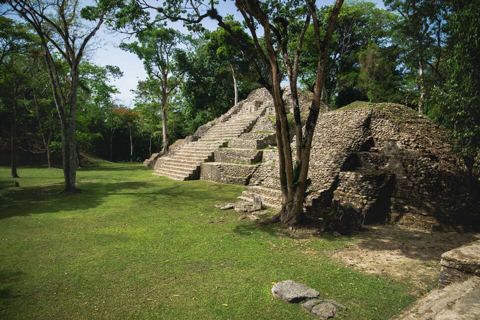 Uma pirâmide de pedra cercada por árvores numa área gramada.