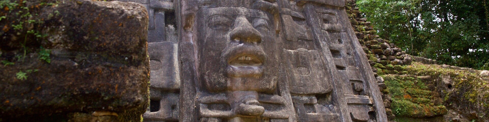 A stone pyramid with intricate carvings and a large face at the top.
