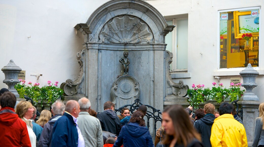 Manneken Pis mostrando um monumento e uma estátua ou escultura assim como um grande grupo de pessoas