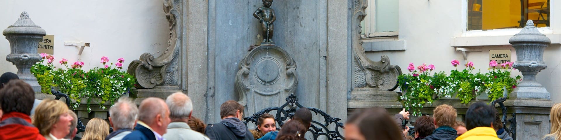 A crowd of people in front of a stone fountain with a statue of a child.