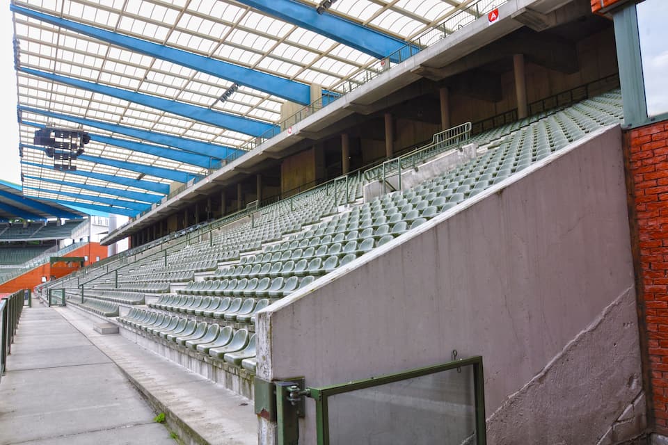 Un grand stade vide, doté de gradins et d’un toit en verre.
