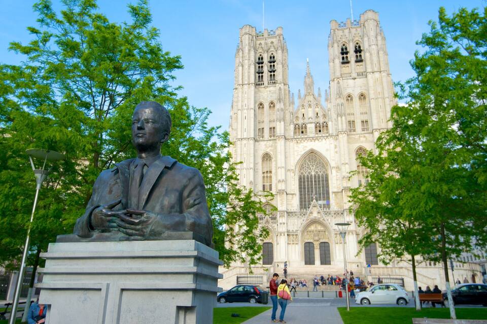 A statue of a man in a suit with a cathedral in the background.