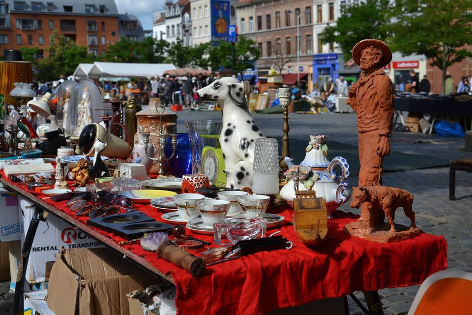Mercado de pulgas con diversos artículos a la venta, incluyendo una figurita de perro dálmata, cerámica y una estatua de una persona.