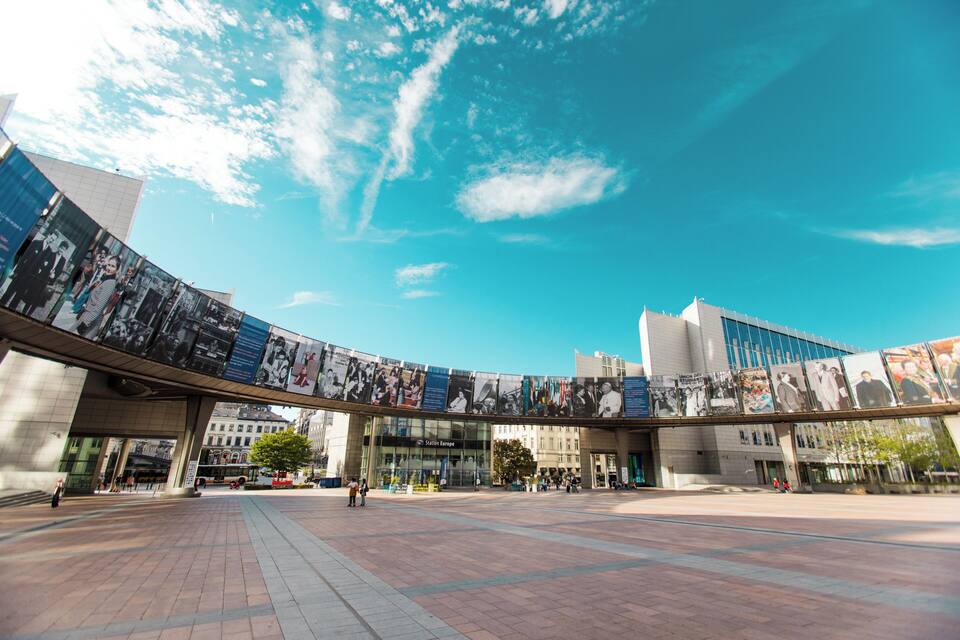 A modern building with a curved glass facade and a large outdoor plaza.