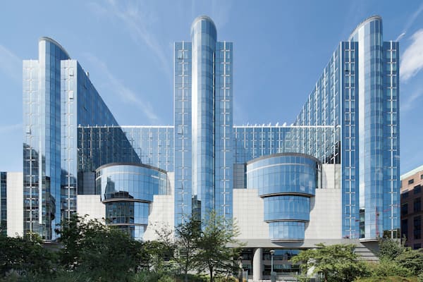 Um edifício moderno em vidro com linhas curvas e angulares, rodeado por vegetação.