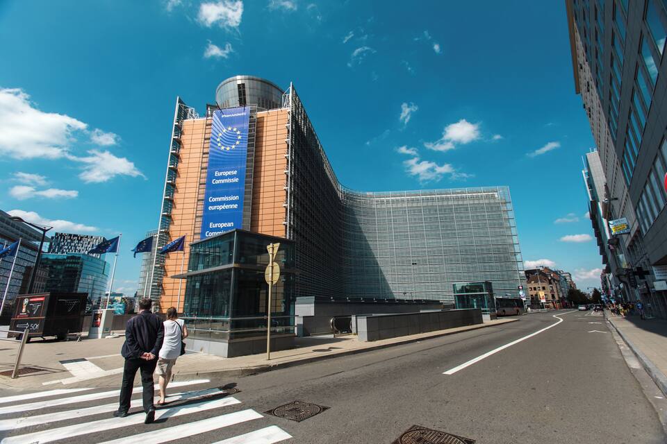 A modern building with a blue flag and a European Commission sign.