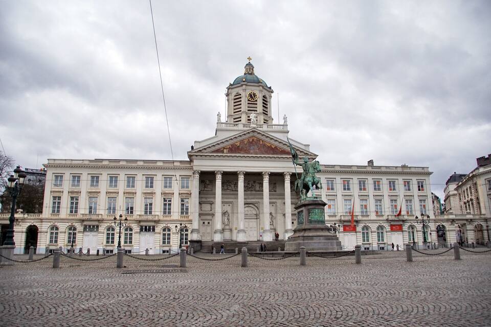 Un edificio histórico con una imponente torre del reloj y estatuas en primer plano.