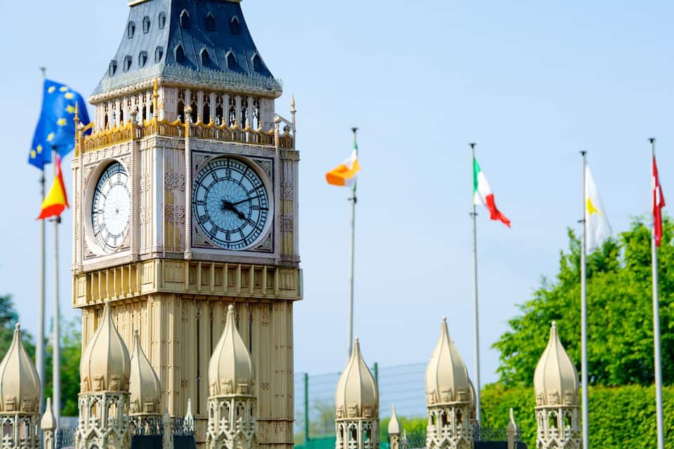 Un beffroi surmonté d’une grande horloge, entouré de différents drapeaux.