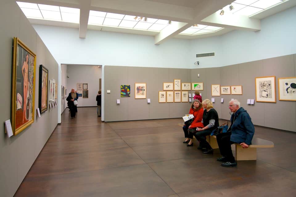 An art gallery with paintings on the walls and a wooden floor.