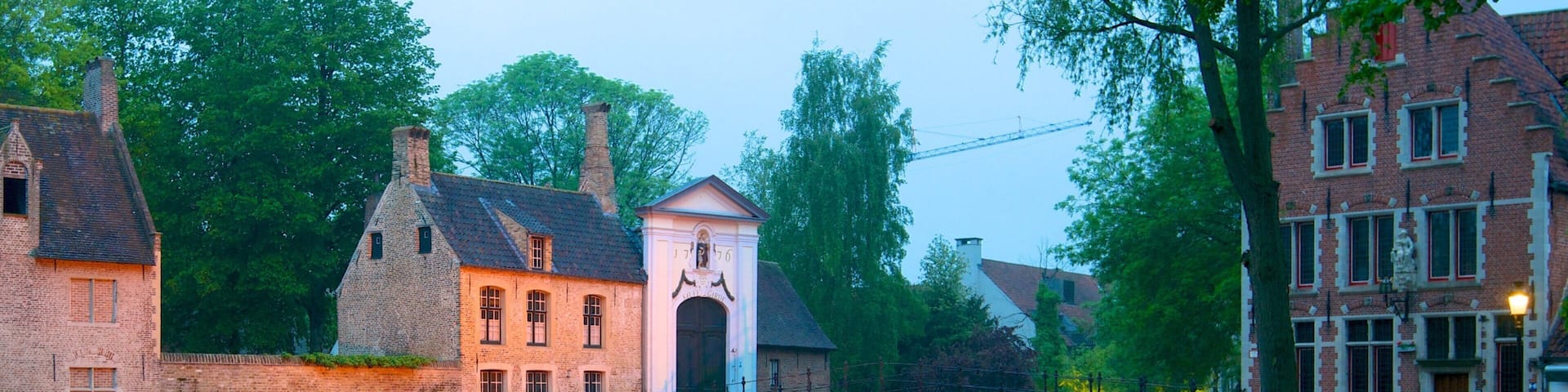 A canal with a bridge, a white building with a clock, and traditional brick houses.