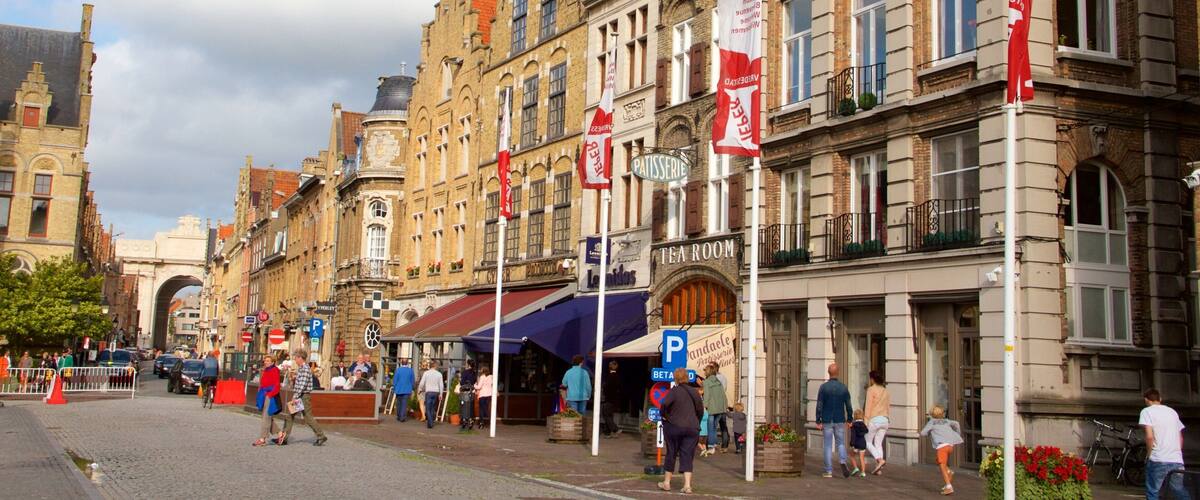 A historic European street with cobblestone pavement, traditional architecture, and flags.