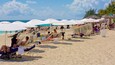 A crowded beach with rows of sun loungers and umbrellas.