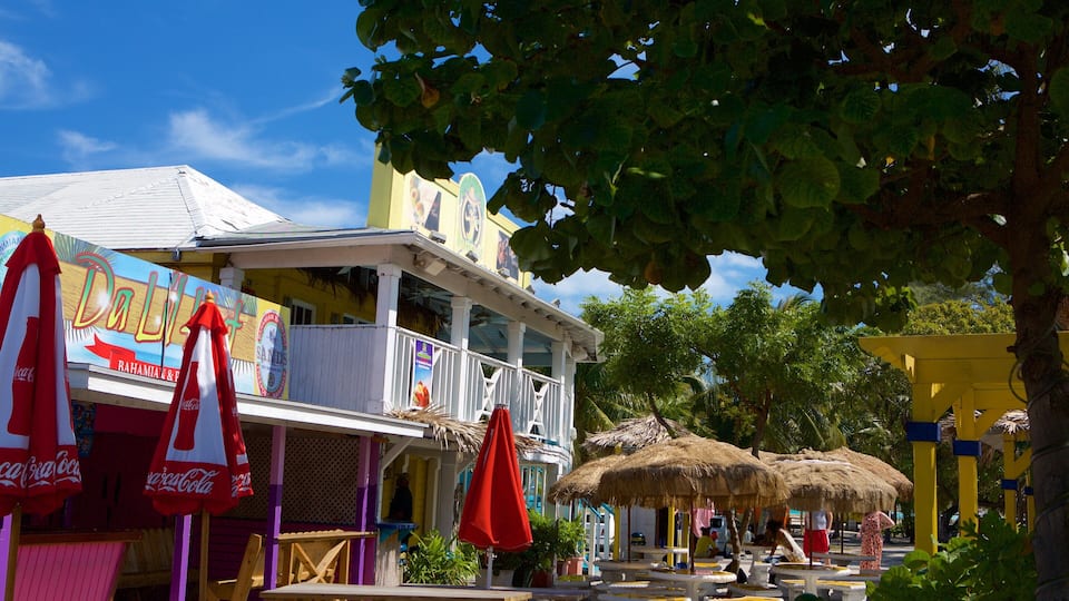 A colorful building with a balcony, surrounded by tropical vegetation and thatched umbrellas.